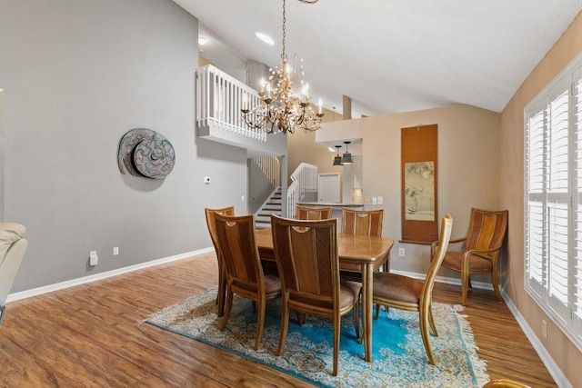 dining space with an inviting chandelier, stairs, wood finished floors, baseboards, and high vaulted ceiling