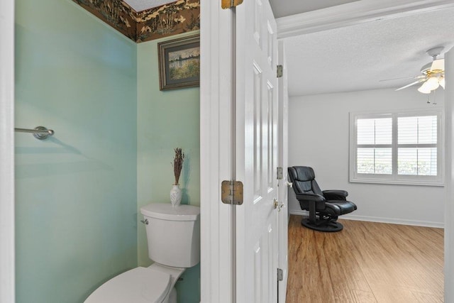 bathroom with baseboards, toilet, a ceiling fan, and wood finished floors