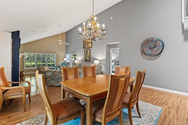 dining room with high vaulted ceiling, baseboards, ceiling fan with notable chandelier, and light wood-type flooring