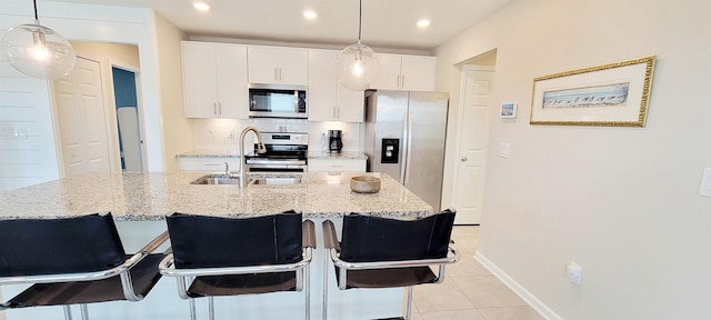 kitchen with white cabinetry, stainless steel appliances, a kitchen breakfast bar, and a center island with sink