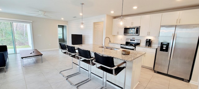 kitchen featuring white cabinetry, appliances with stainless steel finishes, light stone countertops, and sink