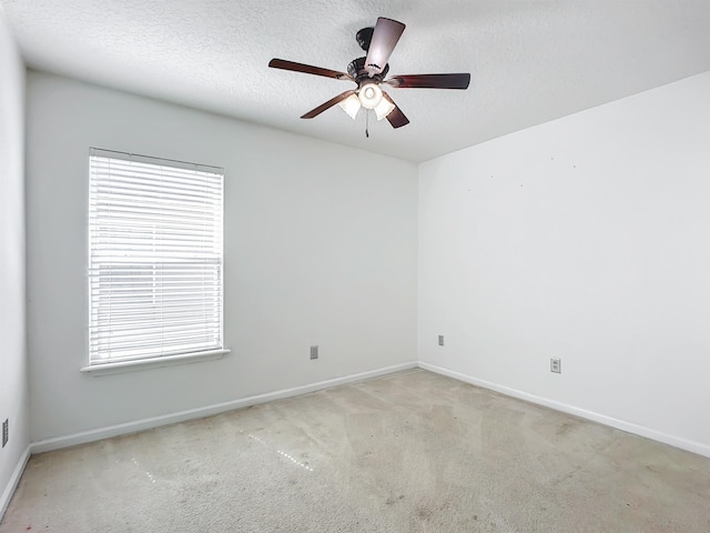 spare room featuring ceiling fan, light colored carpet, and a textured ceiling