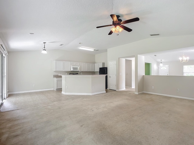 unfurnished living room with a wealth of natural light, light carpet, ceiling fan with notable chandelier, and vaulted ceiling