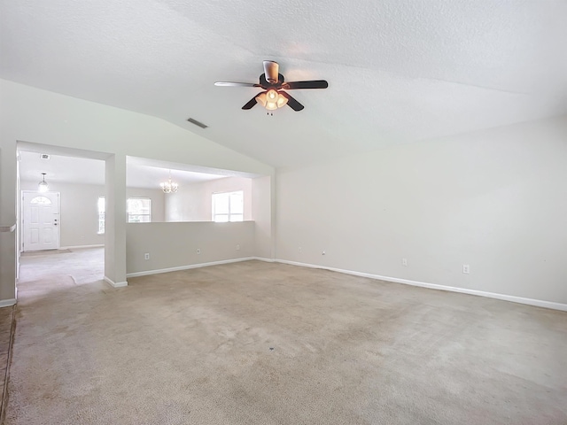 empty room featuring a textured ceiling, ceiling fan with notable chandelier, light colored carpet, and vaulted ceiling