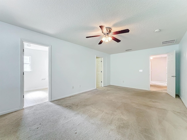 spare room featuring a textured ceiling, ceiling fan, and light carpet