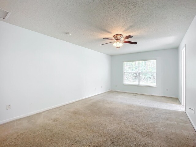 unfurnished room featuring ceiling fan, light colored carpet, and a textured ceiling