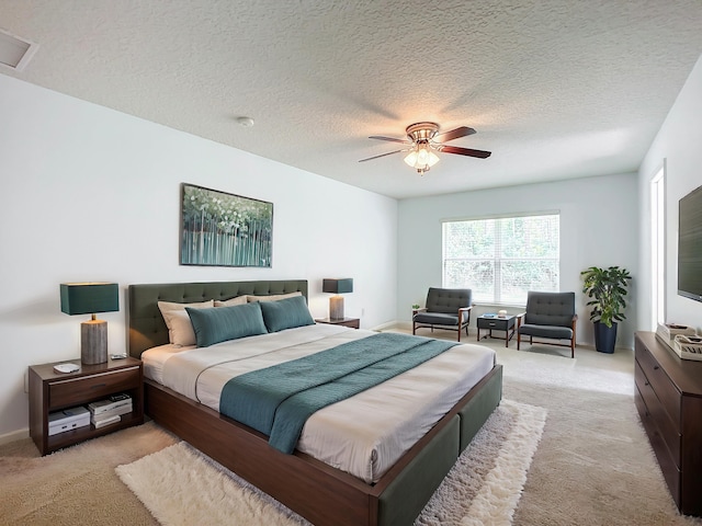 carpeted bedroom featuring ceiling fan and a textured ceiling