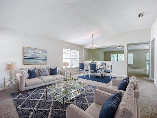 carpeted living room with ceiling fan with notable chandelier and lofted ceiling