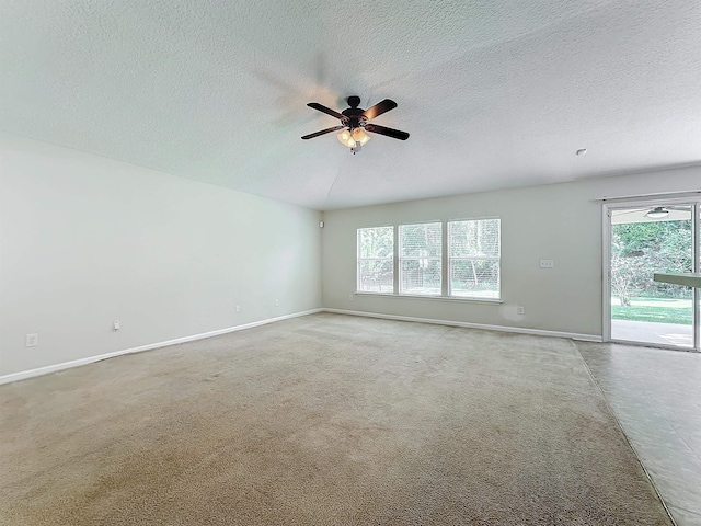 carpeted empty room featuring a textured ceiling, a wealth of natural light, and ceiling fan