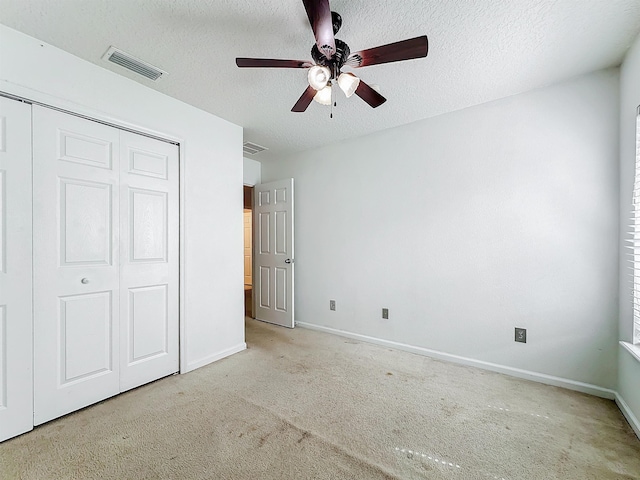 unfurnished bedroom with a textured ceiling, a closet, ceiling fan, and light colored carpet