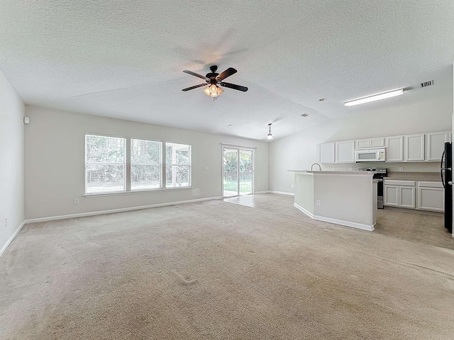 unfurnished living room featuring a textured ceiling, ceiling fan, light colored carpet, and vaulted ceiling