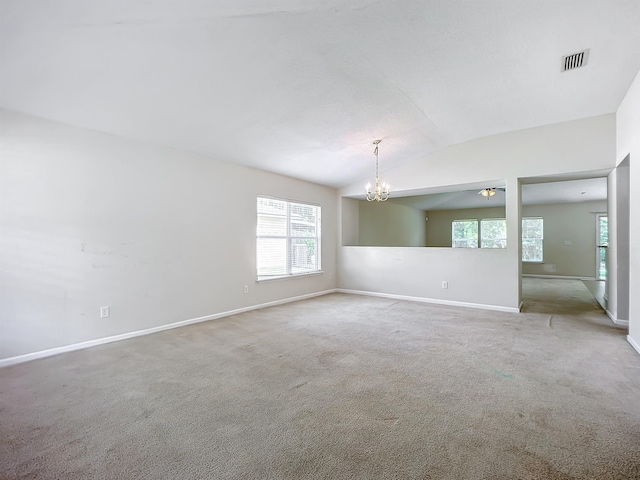 carpeted spare room with ceiling fan with notable chandelier and vaulted ceiling