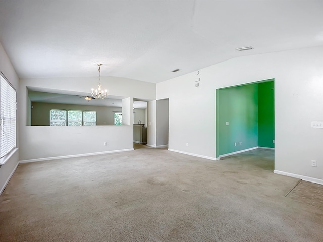 spare room with carpet floors, an inviting chandelier, and lofted ceiling