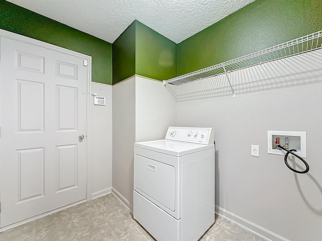 laundry area with light tile patterned floors, a textured ceiling, and washer / clothes dryer