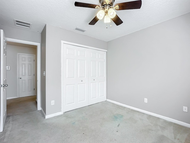 unfurnished bedroom with ceiling fan, a closet, light carpet, and a textured ceiling