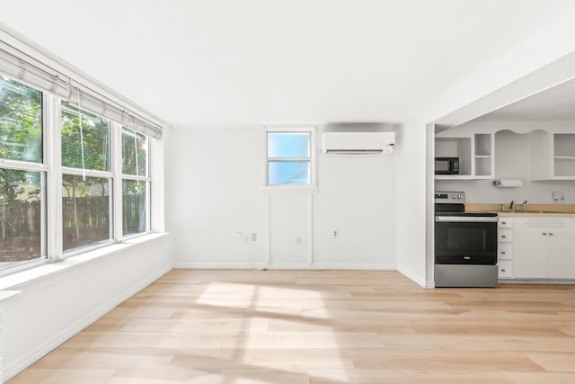 26 Ponce De Leon Ave, Saint Augustine, FL 32080 - kitchen featuring stainless steel electric range oven, a wall unit AC, black microwave, open shelves, and light wood-style flooring