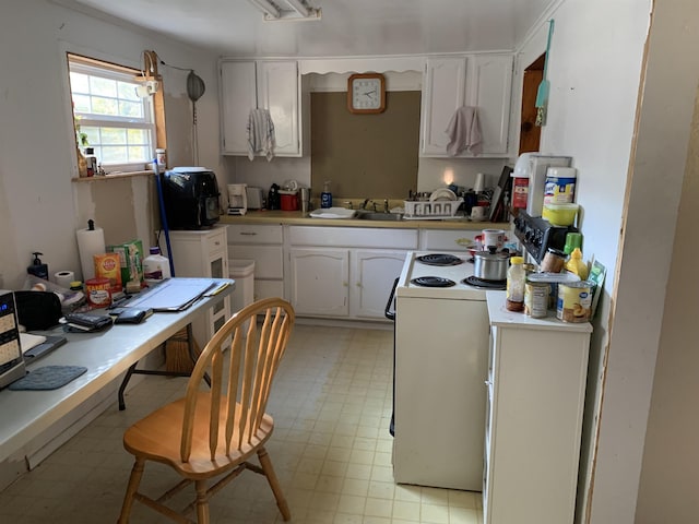 kitchen with electric stove, sink, and white cabinets