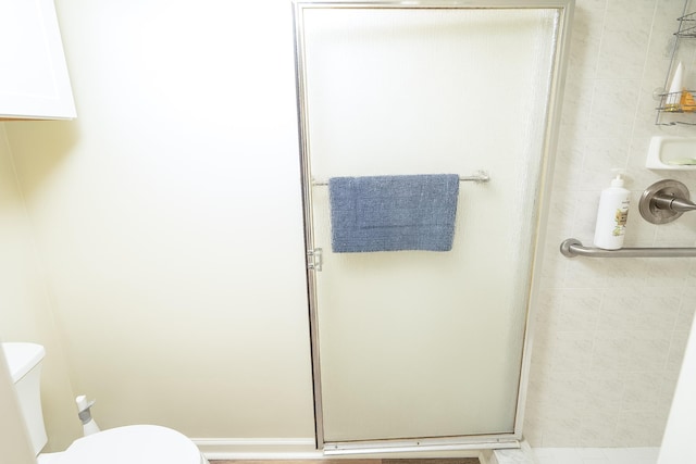 bathroom featuring toilet and a shower with shower door