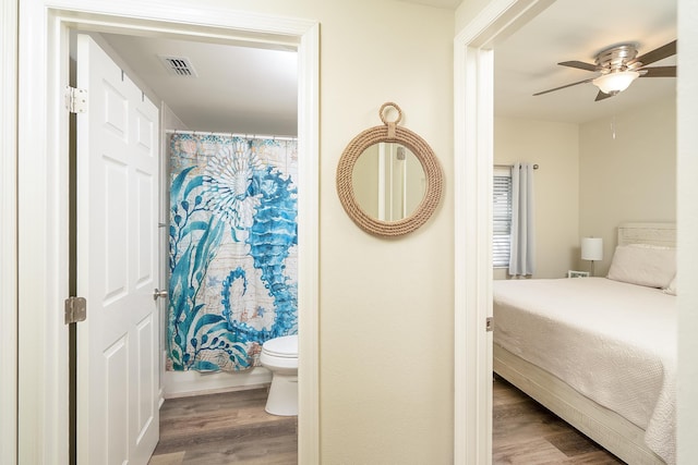 bedroom featuring hardwood / wood-style flooring, ceiling fan, and ensuite bath