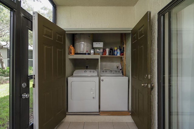 clothes washing area featuring washing machine and dryer, a wealth of natural light, and light tile patterned floors