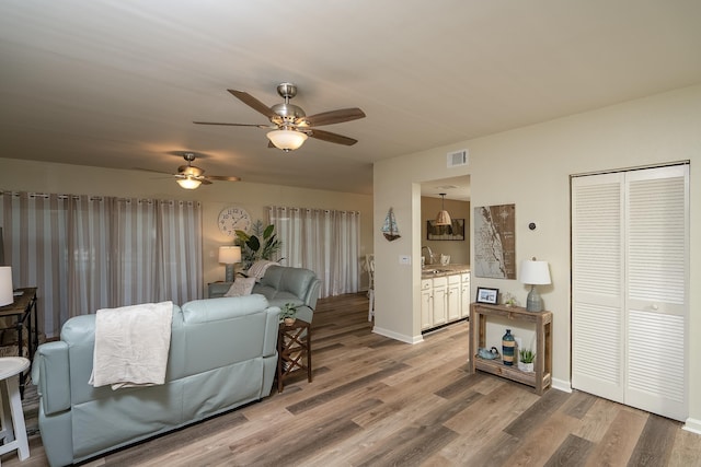 living room featuring ceiling fan, wood-type flooring, and sink