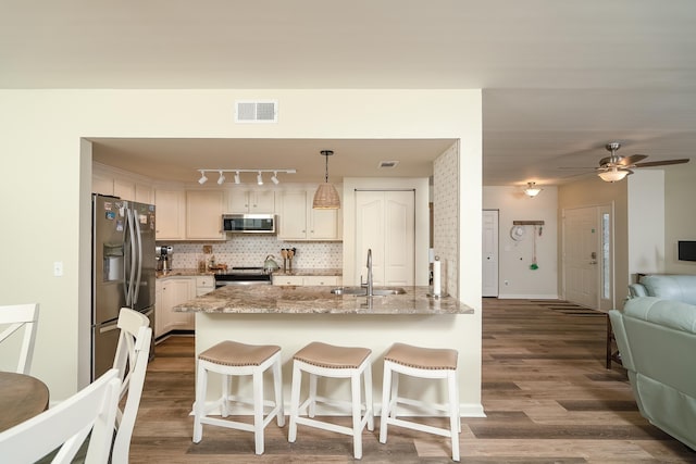 kitchen featuring appliances with stainless steel finishes, sink, backsplash, hanging light fixtures, and kitchen peninsula