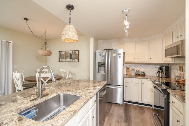 kitchen with sink, white cabinetry, light stone counters, hanging light fixtures, and stainless steel appliances