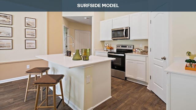 kitchen with a breakfast bar, appliances with stainless steel finishes, white cabinetry, and an island with sink