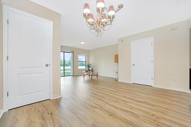empty room featuring light wood-type flooring and a notable chandelier