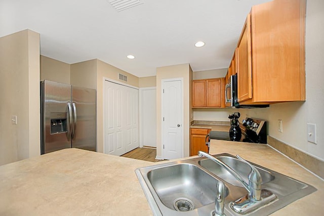 kitchen featuring light wood-type flooring, sink, and appliances with stainless steel finishes