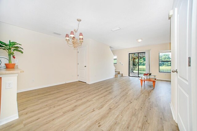 unfurnished living room with a notable chandelier and light wood-type flooring