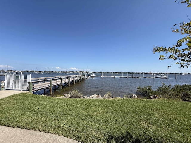 view of dock featuring a lawn and a water view