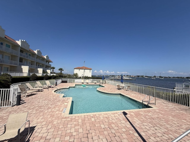 view of swimming pool with a water view and a patio