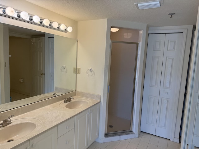 bathroom with tile patterned flooring, vanity, a textured ceiling, and a shower with shower door