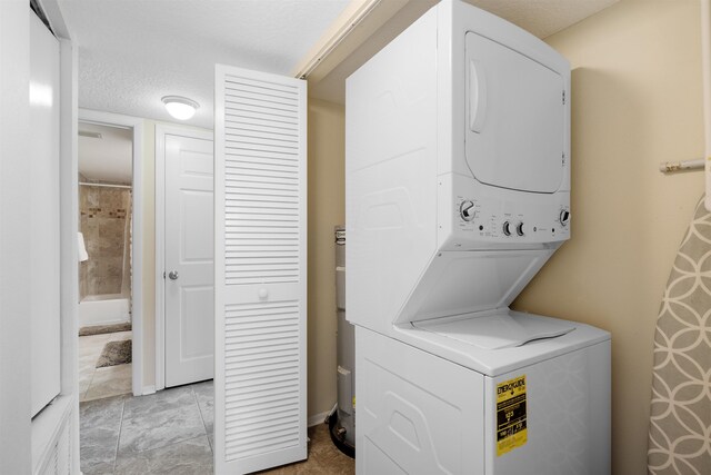 clothes washing area featuring stacked washing maching and dryer and a textured ceiling