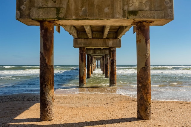 view of dock with a water view and a beach view