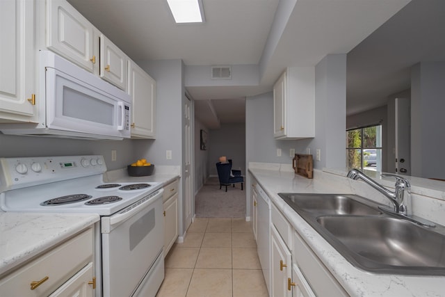 kitchen with sink, white appliances, light tile patterned floors, and white cabinets