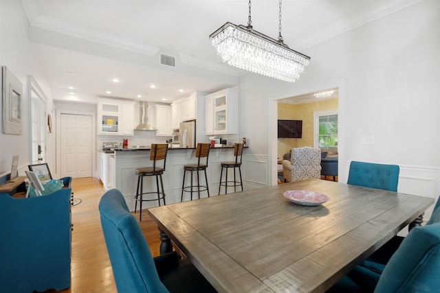 dining area featuring a notable chandelier, crown molding, and light hardwood / wood-style flooring