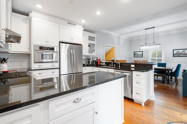 kitchen featuring light wood-type flooring, stainless steel appliances, ventilation hood, decorative light fixtures, and white cabinetry