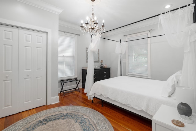 bedroom featuring hardwood / wood-style flooring, a notable chandelier, ornamental molding, and a closet