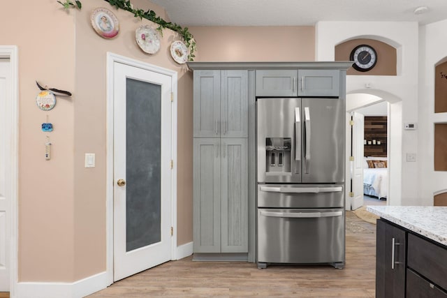 1300 Paradise Pond Rd, Saint Augustine, FL 32092 - kitchen featuring stainless steel refrigerator with ice dispenser, light wood-type flooring, light stone counters, arched walkways, and gray cabinetry