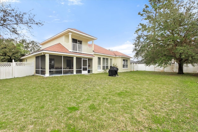 rear view of property featuring a balcony, a lawn, and a sunroom