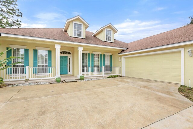 cape cod home featuring a garage and covered porch