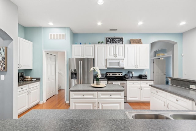 kitchen with white cabinetry, appliances with stainless steel finishes, light hardwood / wood-style flooring, and a center island