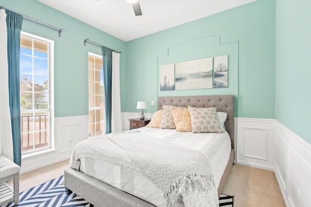 bedroom featuring ceiling fan, light colored carpet, and multiple windows