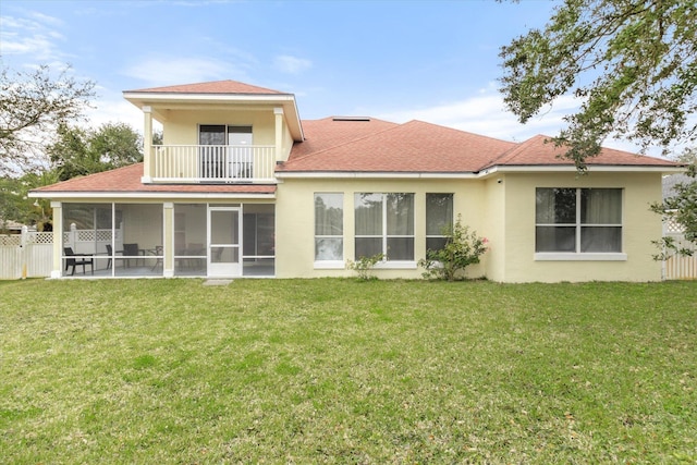 rear view of house featuring a balcony, a yard, and a sunroom