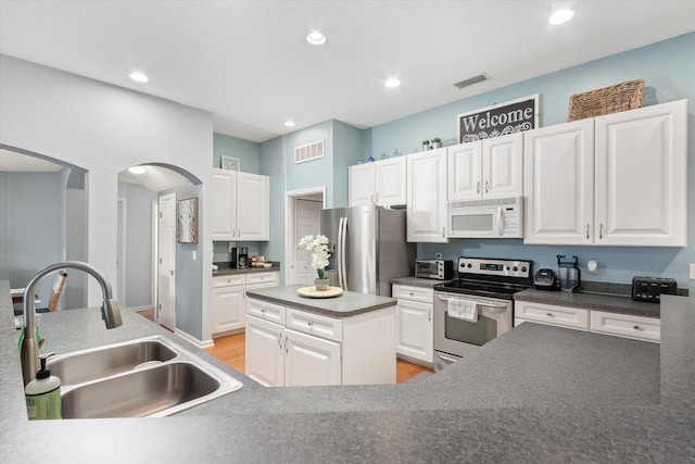 kitchen featuring sink, stainless steel appliances, a center island, and white cabinetry