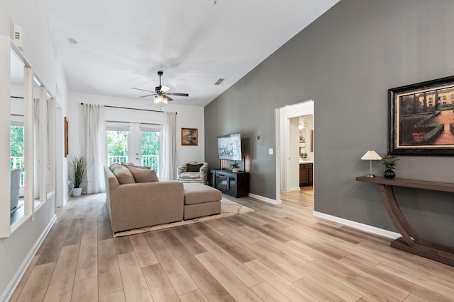 living room featuring ceiling fan, light hardwood / wood-style floors, high vaulted ceiling, and french doors