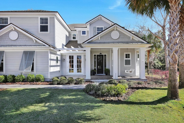 view of front of house with covered porch, a front lawn, and a shingled roof