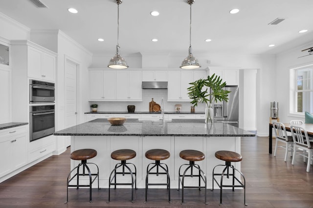 200 Manuel Ct, Saint Augustine, FL 32095 - kitchen featuring under cabinet range hood, ornamental molding, appliances with stainless steel finishes, white cabinetry, and a kitchen island with sink